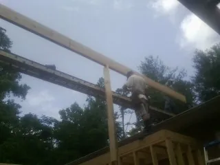 Carpenter setting a ridge beam over a new addition frame — Ice Dam Removal by Roofing Brothers in Winnie