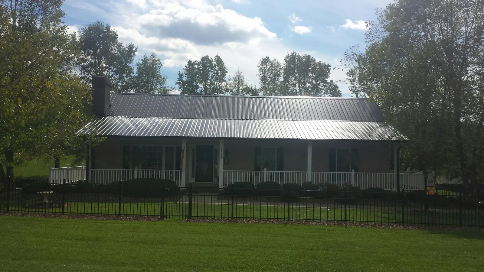 Gray metal roof on a brick ranch with a full width front porch — Gutter Guard Installation work by our crew in Winnie