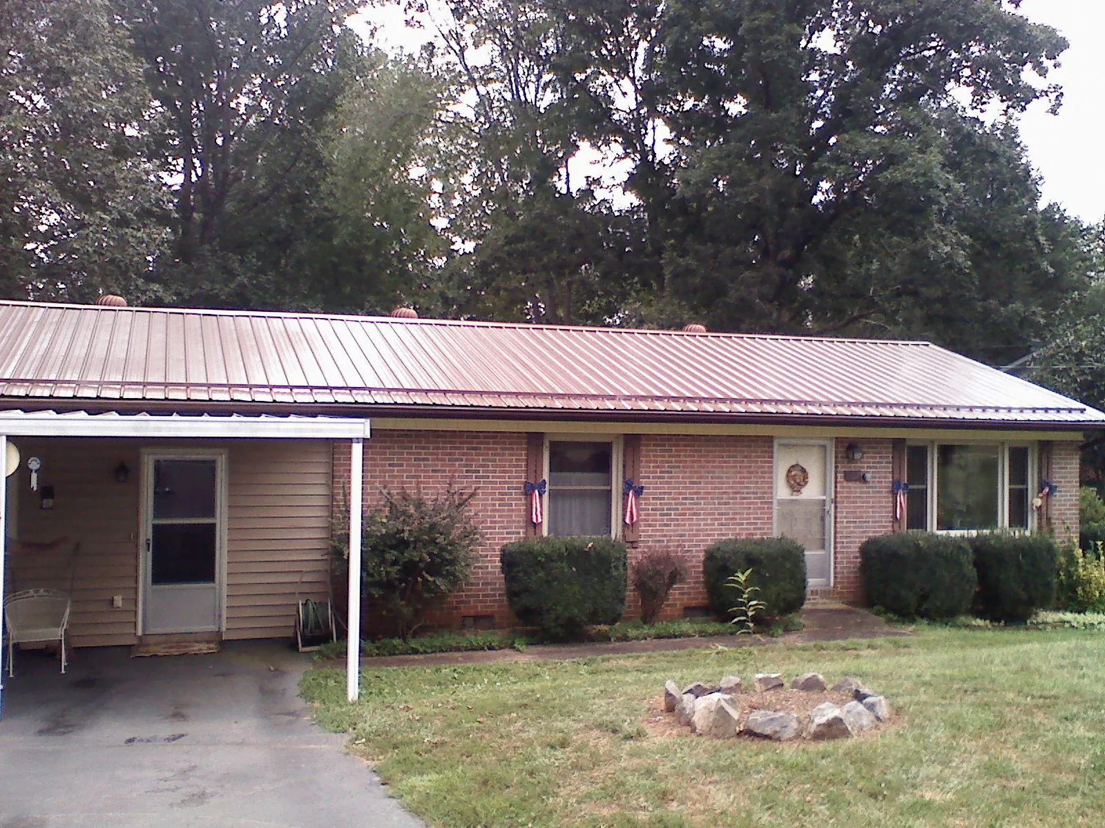Bronze metal roof and carport on a brick ranch home — Roof Repair work by our crew in Winnie