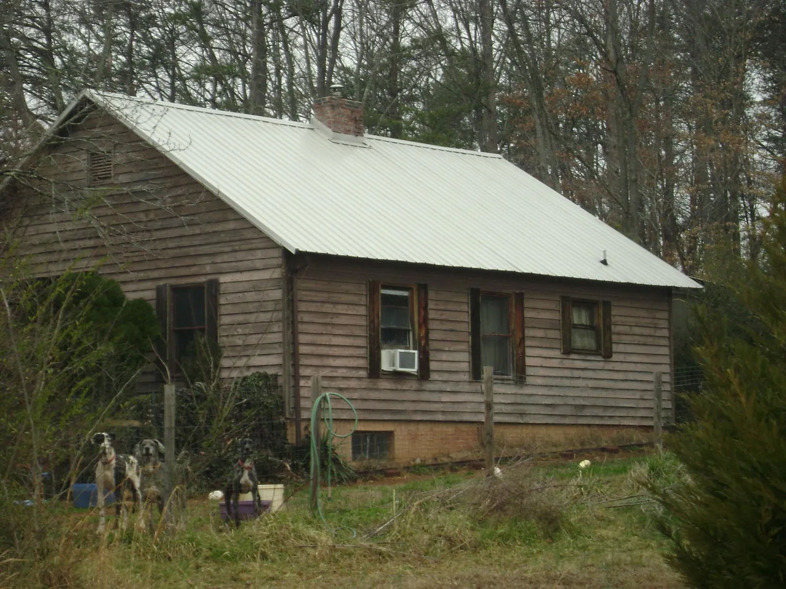 White metal roof on an old wood sided farmhouse, from a Metal Roof Installation job in Winnie